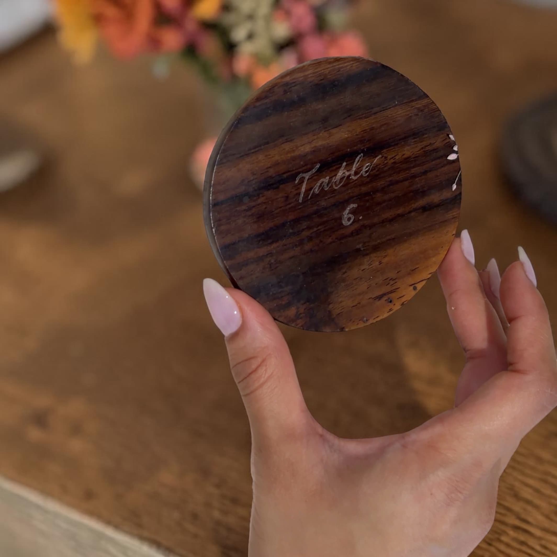 Personalized lettering on a round wooden table marker